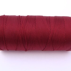 May include: A spool of maroon colored thread.