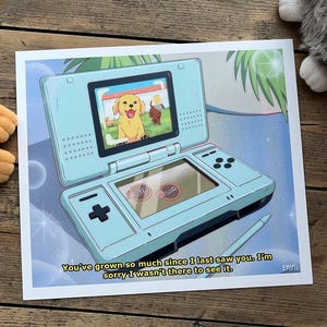 Puede incluir: Una impresión azul claro que representa una consola de juegos portátil retro con una pantalla que muestra un perro de dibujos animados. La impresión incluye el texto "You've grown so much since I last saw you. I'm sorry I wasn't there to see it."