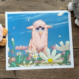Puede incluir: Una impresión que muestra una criatura rosa parecida a un Furby en un campo de flores bajo un cielo azul. La imagen tiene un estilo caprichoso, inspirado en el anime. El texto en la parte inferior dice: "May flowers grow in the saddest parts of you."