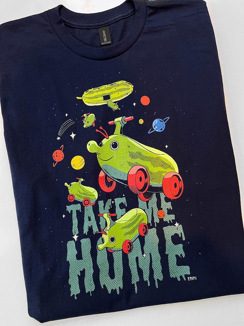 Peut inclure: T-shirt bleu marine avec un motif fantaisiste de sauteurs spatiaux verts avec des roues rouges et un th&egrave;me spatial. Le texte "TAKE ME HOME" est imprim&eacute; dans une police d&eacute;goulinante. Des plan&egrave;tes et des &eacute;toiles sont &eacute;galement incluses.