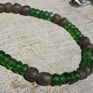 May include: A necklace made of dark grey and green glass beads. The beads are strung on a silver chain.