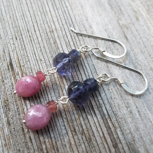 May include: A pair of dangle earrings with pink and purple gemstone beads and silver hooks.