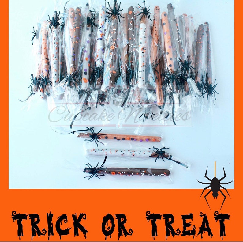 May include: A collection of chocolate-covered pretzel sticks decorated with Halloween-themed sprinkles and black spider accents. The pretzel sticks are individually wrapped in clear cellophane bags and arranged on a white surface. The text "TRICK OR TREAT" is written in black dripping letters on an orange background.