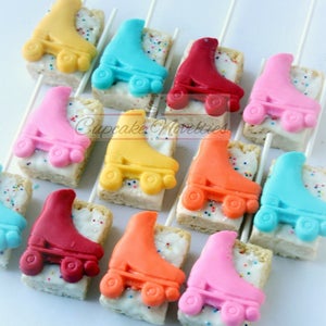May include: Assortment of colorful roller skate shaped cake pops on sticks. The cake pops are decorated with white frosting and colorful sprinkles. The roller skates are in various colors including yellow, blue, red, pink, orange, and turquoise.