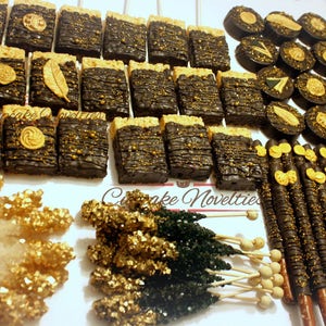 May include: Assortment of black and gold chocolate-covered treats, including rice krispie treats, pretzel sticks, and chocolate-covered pretzels. The treats are arranged on a white surface with gold and black sprinkles.
