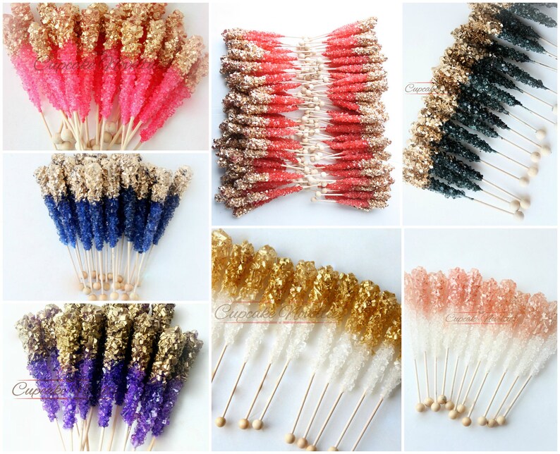 May include: Assortment of colorful rock candy sticks with gold glitter on top. The candy sticks are arranged in groups of different colors, including pink, blue, purple, and white. Each stick is attached to a wooden stick with a round wooden bead at the end.