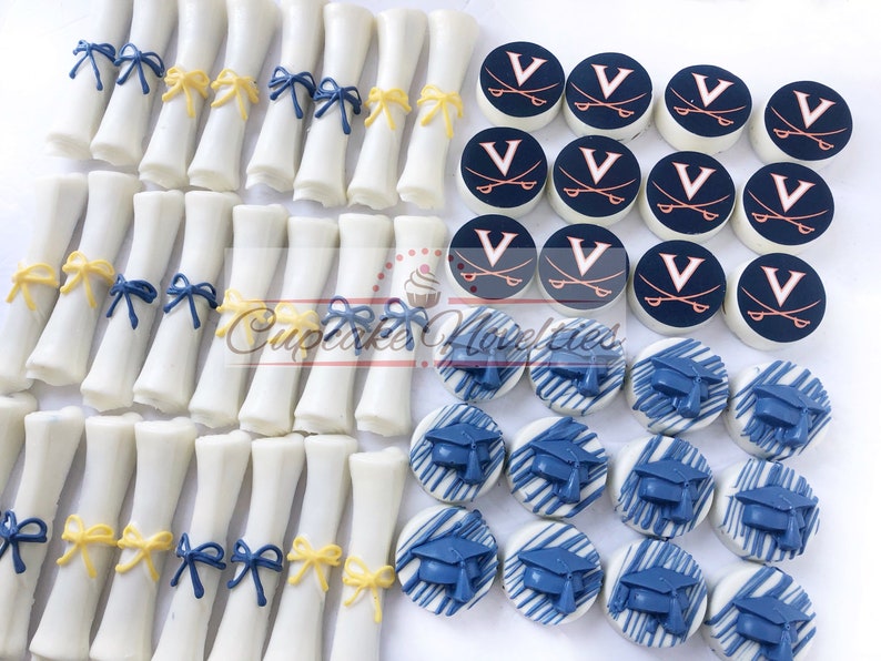 May include: Assortment of graduation-themed chocolate treats. White chocolate diplomas with blue and yellow ribbon accents. White chocolate round cookies with blue and white graduation caps and white chocolate round cookies with a navy blue background and a white "V" with crossed swords in orange.