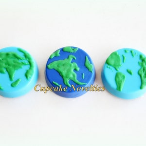 May include: Three round chocolate treats decorated with blue and green icing to resemble the Earth. The text "Cupcake Novelties" is visible in the image.