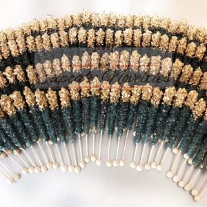 May include: A large group of gold and teal rock candy sticks on white sticks. The candy is arranged in a semi-circle shape.