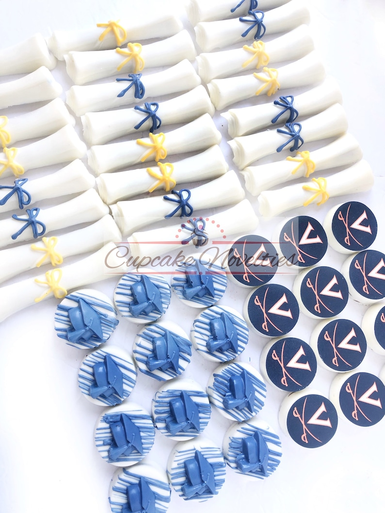 May include: A collection of graduation-themed treats, including white chocolate diplomas tied with blue and yellow ribbons, and round chocolate cookies decorated with blue graduation caps and white chocolate drizzle.