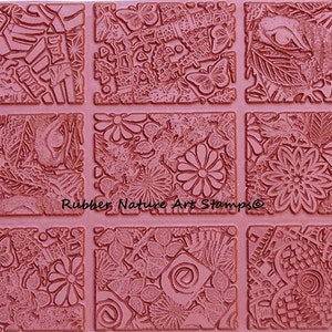 May include: A set of nine rubber stamps with various floral and geometric designs. The stamps are arranged in a 3x3 grid and are all in a reddish-brown color. The text "Rubber Nature Art Stamps" is printed in the center of the image.
