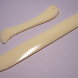 May include: Two ivory-colored bone folders, one with a rounded tip and the other with a pointed tip.