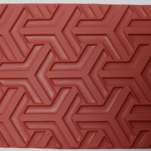 Puede incluir: Un sello de goma rojo con un patrón geométrico repetitivo de triángulos entrelazados.