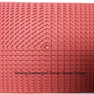 Puede incluir: Sellos de textura de goma roja con un patrón repetitivo de pequeños triángulos. El sello está diseñado para crear un efecto texturizado en papel u otras superficies. El texto "Smiling Summergirl Texture Stamp Listing" es visible en la parte inferior del sello.