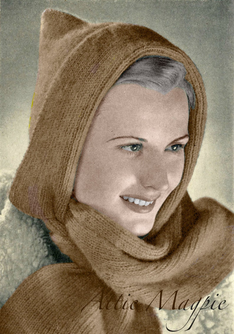 Peut inclure: Une femme portant une &eacute;charpe &agrave; capuche en tricot marron. L'&eacute;charpe est pli&eacute;e et la capuche est tir&eacute;e sur sa t&ecirc;te. La femme sourit et regarde sur le c&ocirc;t&eacute;. Le texte "Attic Magpie" est visible dans le coin inf&eacute;rieur droit de l'image.