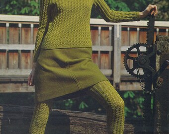 Peut inclure: Une femme portant un pull et une jupe en tricot vert avec des collants verts assortis. Elle se tient sur une plateforme en bois avec un engrenage métallique en arrière-plan.