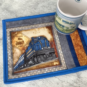 May include: Blue and gray train coaster with a blue border. The coaster features a train with a yellow sign that reads "Train Xing".