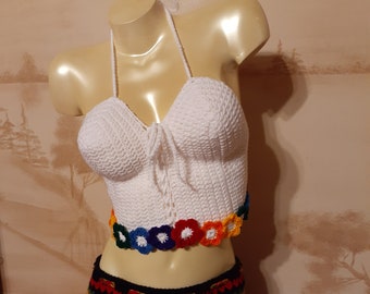 Può includere: Top bianco all'uncinetto con un bordo arcobaleno di fiori all'uncinetto. Il top è su un manichino.