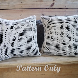 May include: Two white crocheted pillow covers with a floral design. The pillows are sitting on a wooden surface. The text "Pattern Only" is written on the surface below the pillows.