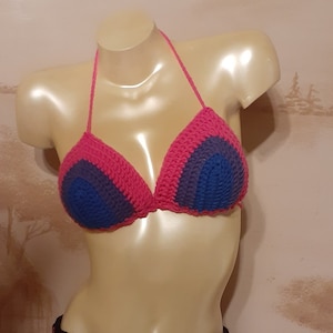 May include: A crocheted bikini top in a pink, purple and blue colour scheme. The top is halter style with a tie at the neck.