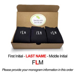 May include: A box containing three pairs of black socks with white embroidered initials "FLM". The box is brown and has a sticker that says "Specially made just for you".