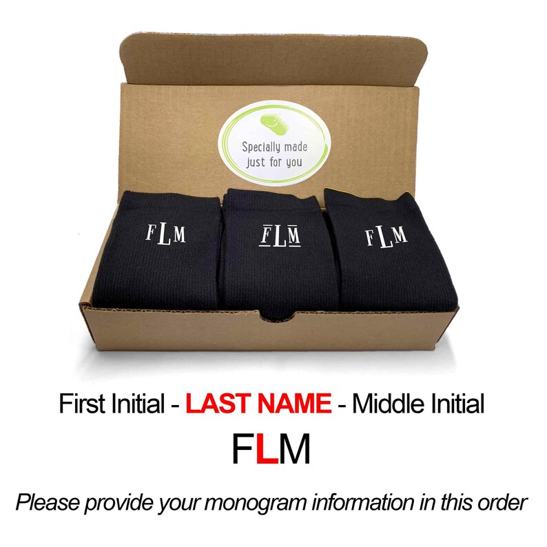 May include: A box containing three pairs of black socks with white embroidered initials "FLM". The box is brown and has a sticker that says "Specially made just for you".