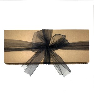 May include: A brown cardboard box with a black tulle ribbon tied in a bow.