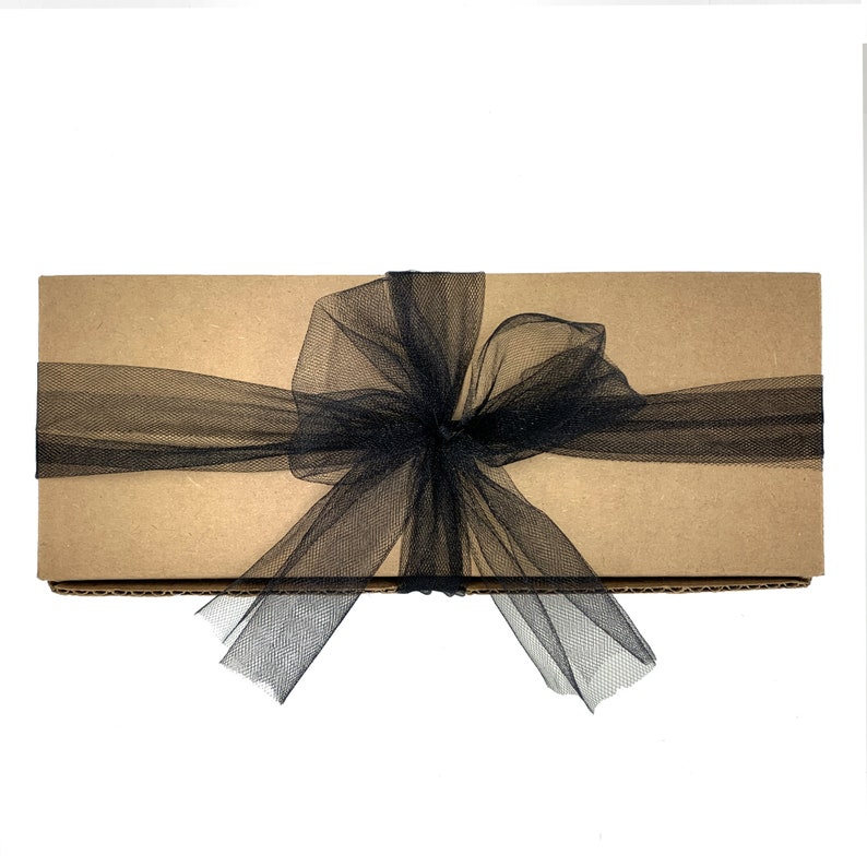 May include: A brown cardboard box with a black tulle ribbon tied in a bow.