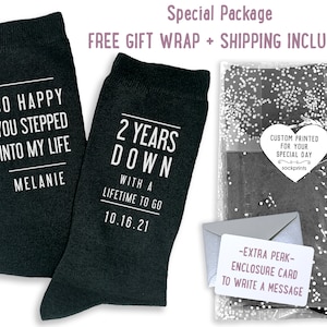 May include: Two black socks with white text. One sock says "So happy you stepped into my life Melanie". The other sock says "2 years down with a lifetime to go 10.16.21".