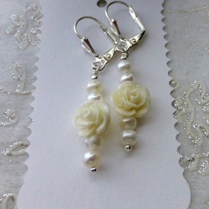 May include: A pair of white pearl and white rose flower earrings with silver hooks.