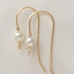 May include: A pair of gold earrings with a single white pearl on each earring.