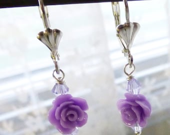 Peut inclure: Une paire de boucles d'oreilles pendantes en argent avec des breloques de roses lavande et des accents de cristal transparent.