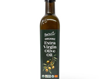 May include: A dark green glass bottle of Food to Live Organic Extra Virgin Olive Oil. The label features text and an illustration of olives on a branch. The bottle contains 16.9 fl oz (500 ml) of olive oil.
