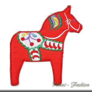 Pode incluir: Cavalo Dala vermelho bordado com detalhes brancos, verdes, azuis e amarelos. O cavalo é um design tradicional de arte popular sueca.