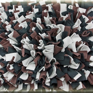 Könnte beinhalten: Eine handgefertigte Hunde-Anreicherungsmatte mit braunen, schwarzen und weißen Stoffstreifen. Die Matte ist so konzipiert, dass sie Hunden mentale Stimulation und Bewegung bietet.