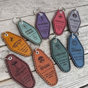 May include: A collection of leather keychains in various colors, each with a unique design and text. Keychains include "Prancing Pony", "Minas Tirith", "Rivendell", "Mordor", "Isengard", "The Green Dragon", "The Shire", "Lothlorien", and "Mines of Moria".