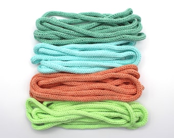 May include: Four bundles of colorful knitted rope in shades of green, blue, orange, and lime green. The ropes are arranged horizontally against a white background. The knitted texture is visible, suggesting a craft or DIY project.