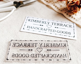 May include: A black and white rubber stamp with the text "KIMBERLY TERRACE HANDCRAFTED GOODS" in a decorative font. The text is mirrored and includes a heart symbol.