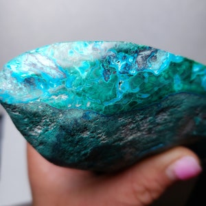 May include: A large, irregularly shaped piece of turquoise gemstone with a deep blue-green color and white and black marbling. The stone has a rough, natural texture.