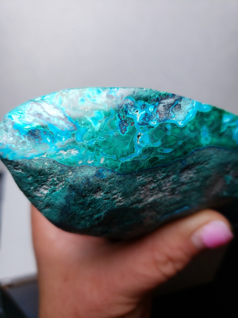 May include: A large, irregularly shaped piece of turquoise gemstone with a deep blue-green color and white and black marbling. The stone has a rough, natural texture.
