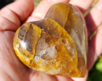 May include: A heart-shaped crystal with a clear, translucent base and yellow and brown inclusions. The crystal is polished and has a smooth, glossy finish.