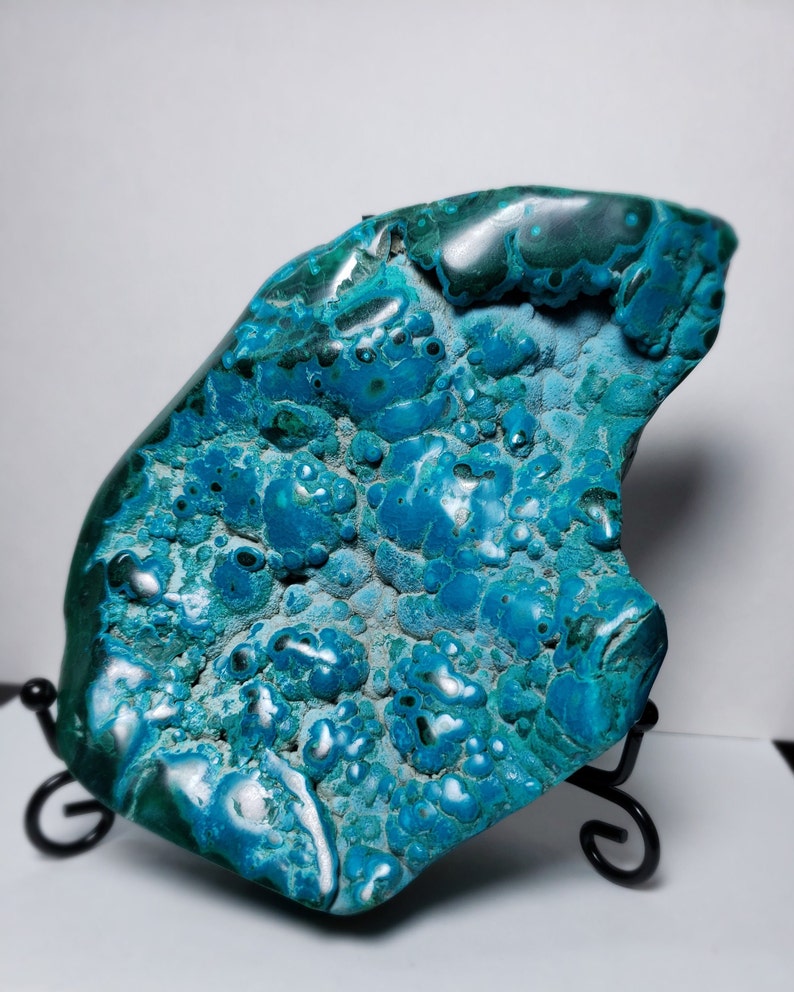 May include: A large, irregularly shaped piece of blue and green chrysocolla with a smooth, polished surface. The stone has a unique, marbled pattern with a variety of shades of blue and green.