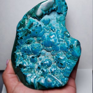 May include: A large, irregularly shaped piece of blue and green chrysocolla. The stone has a smooth, polished surface with a swirling pattern of blue and green.