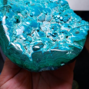 May include: A large, teal blue and green, polished, natural stone with a unique, bubbly texture. The stone has a smooth, rounded surface and a rougher, textured underside.