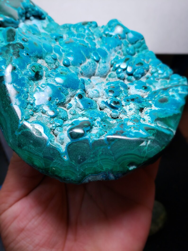 May include: A large, teal blue and green, polished, natural stone with a unique, bubbly texture. The stone has a smooth, rounded surface and a rougher, textured underside.