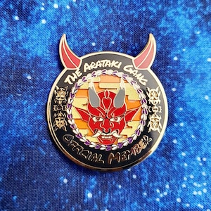 Peut inclure: Une épingle en émail noir et or avec un visage de démon rouge au centre. L'épingle indique "The Arataki Gang Official Member" autour du bord.
