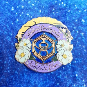 Puede incluir: Un pin de esmalte morado y dorado con un diseño estilizado de un marco hexagonal con un círculo interior azul y dorado. El pin tiene el texto "Yashiro Commission Kamisato Clan" alrededor del borde exterior.