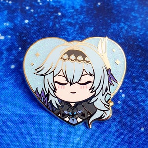 May include: A heart-shaped enamel pin featuring a cartoon character with long, light blue hair, closed eyes, and a light blue and black outfit. The pin has a sparkly, iridescent background.