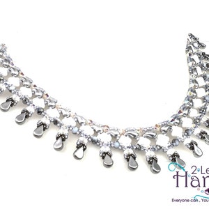 May include: A white and silver beaded necklace with a teardrop design. The necklace is made with small beads and has a delicate, feminine look. The necklace is accented with silver beads and has a teardrop design.
