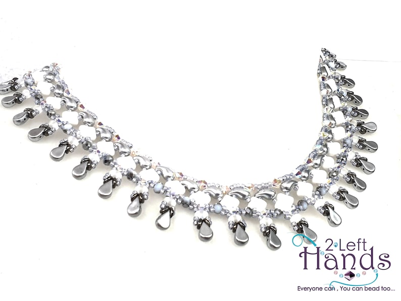 May include: A white and silver beaded necklace with a teardrop design. The necklace is made with small beads and has a delicate, feminine look. The necklace is accented with silver beads and has a teardrop design.